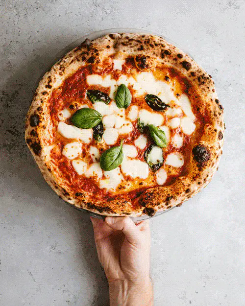 Zrzut ekranu strony marki Impasto — dłoń trzymająca świeżo upieczoną pizzę