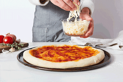 Posypywanie rozciągniętego ciasta świeżą mozzarellą